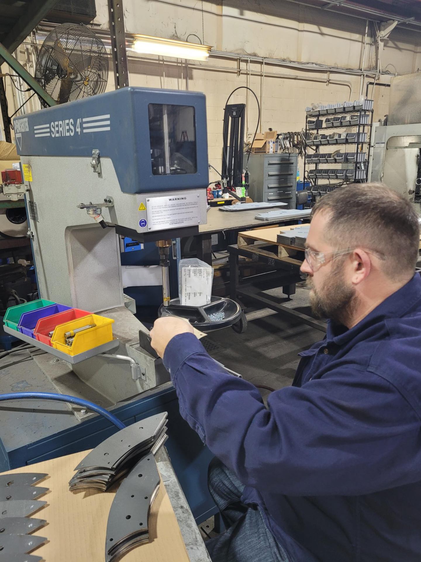Worker operating a pemserter/riveting machine for hardware insertion