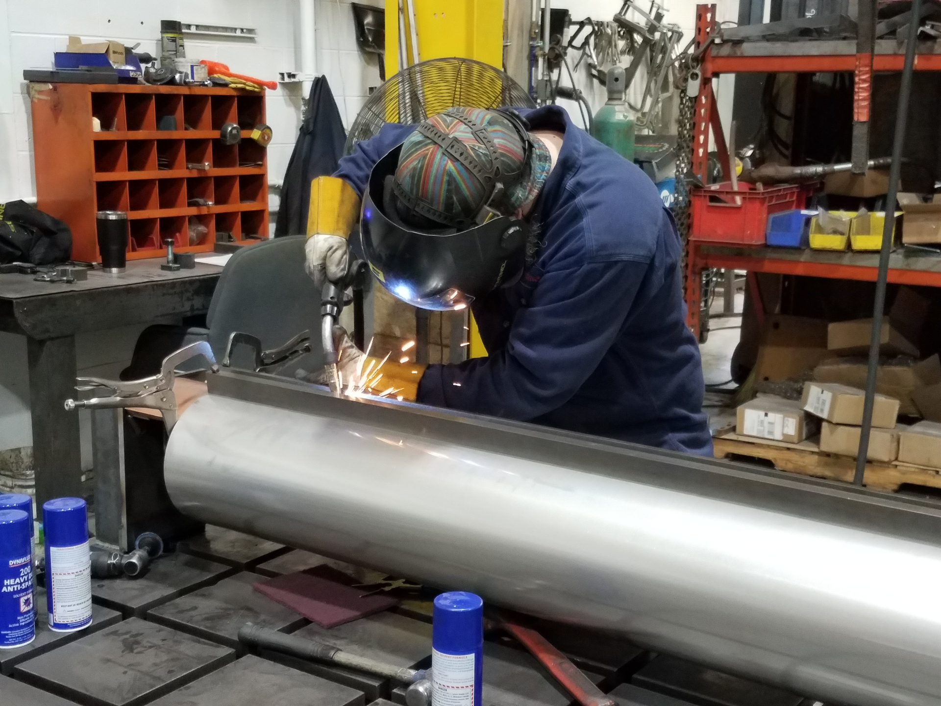 Expert welder working on stainless steel tube with sparks flying