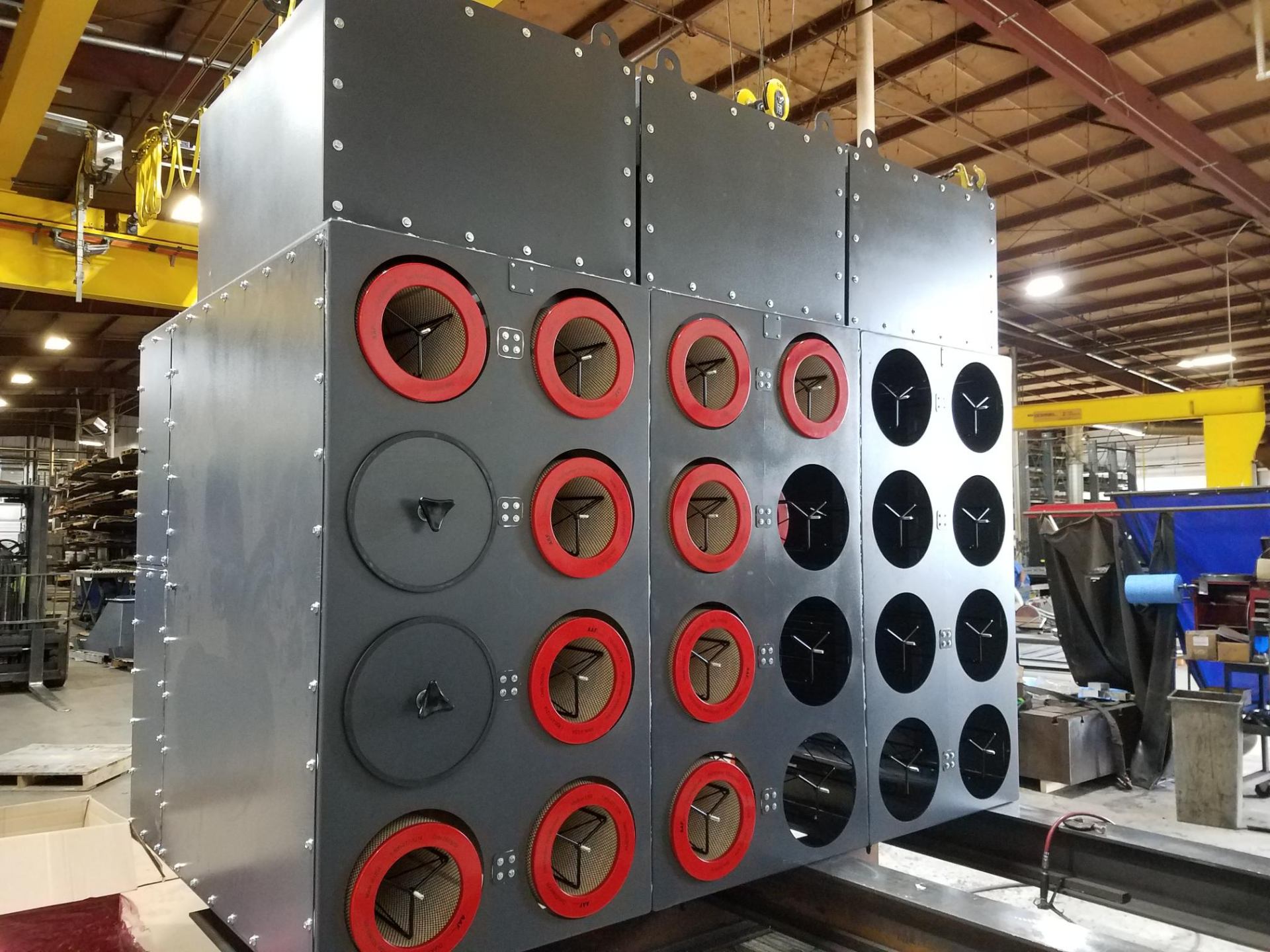 Large industrial filter housing with red and black ports fabricated on shop floor